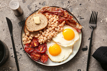 Plate of tasty English breakfast with fried eggs on grey background