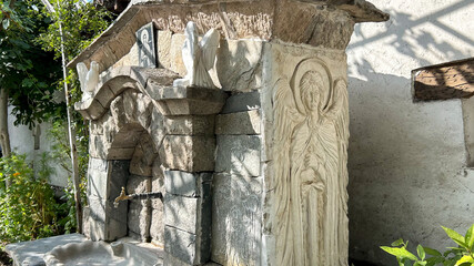 Historic Stone Fountain With Angel Carving And Religious Icon, Sunlit Garden Setting, Symbol Of...
