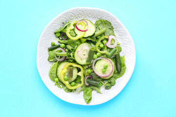 Plate of fresh vegetable salad on blue background