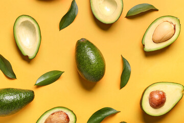 Fresh ripe avocados and leaves on orange background