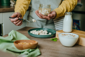 Males hands holding tofu on a fork over a jar