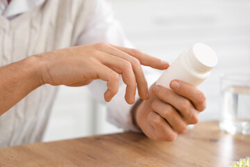 Young man reading pills description at home, closeup
