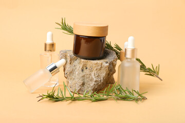 Composition with bottles of cosmetic products, rosemary, jar and stone on color background