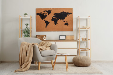 World map on wall, armchair, chest of drawers and shelving units in interior of living room