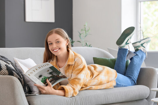 Young woman reading interior design magazine on sofa at home