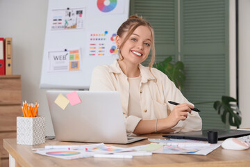 Female web designer with graphic tablet working at table in office