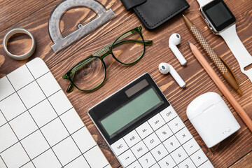 Composition with different stationery, earphones and smart watch on wooden background