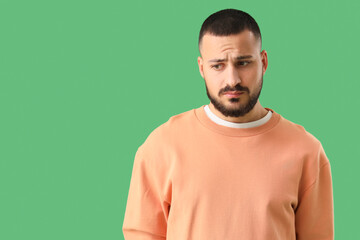 Apologetic young man on green background
