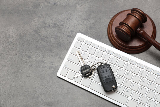 Car key with computer keyboard and auction gavel on dark background