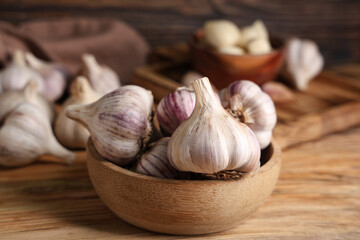 Bowl with fresh garlic on wooden background