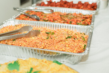 Trays of Korean side dishes and seasoned vegetables in catering aluminum trays