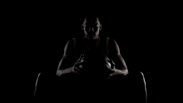 Basketball player sitting on a bench. Concentrated african american sports man against black background.