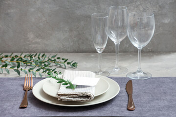 Stylish table setting with blank card and cloth on grey background. Closeup