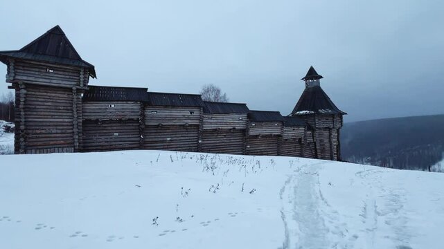 A log fortress wall covered with snow after a blizzard. Scenery for the film "The Heart of Parma" among snow-covered forests, hills and mountains in Perm Krai, Russia. The crooked cross in the Lip.4K