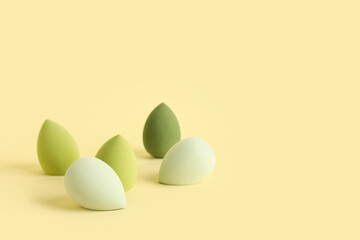 Green makeup sponges on yellow background