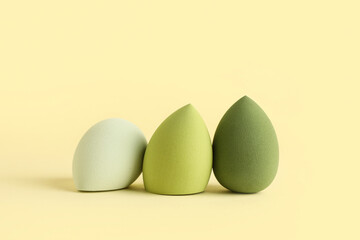 Green makeup sponges on yellow background