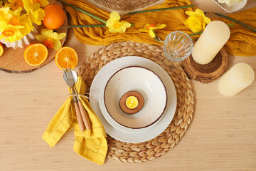 Elegant table setting with beautiful narcissus flowers, candles and fresh oranges, top view