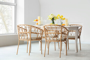 Elegant table setting with beautiful narcissus flowers and candles in light dining room