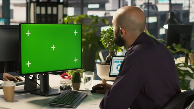 Employee at work using isolated screen PC to check progress done on customer commissioned project. Office clerk in front of mockup computer reading data statistics on paperwork after audit, camera A
