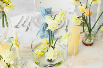 Beautiful table setting with narcissus flowers in room, closeup