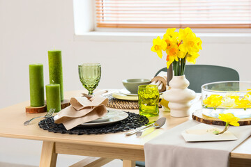 Beautiful table setting with narcissus flowers in room