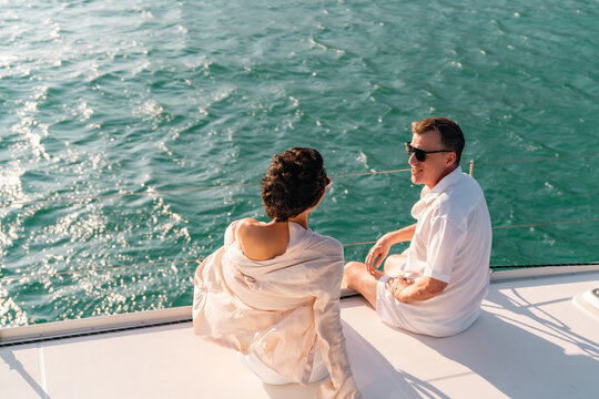 Caucasian couple travel nature the sea on luxury catamaran boat yacht on summer beach holiday vacation. Couple enjoy outdoor lifestyle relaxing and drinking champagne on cruise ship yacht at sunset.