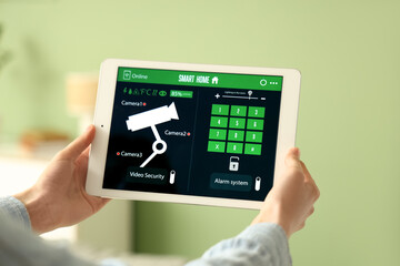 Female hands with smart home security system control panel in room, closeup