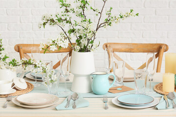 Elegant table setting with plates, glasses and blooming tree branches