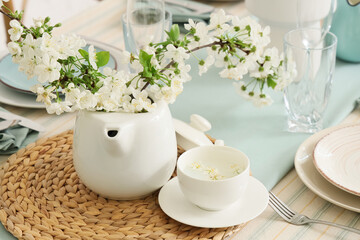Elegant table setting with plates, tea cup and blooming tree branches, closeup