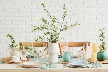 Elegant table setting with plates, glasses and blooming tree branches