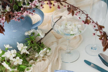 Elegant table setting with glasses and blooming tree branches, closeup