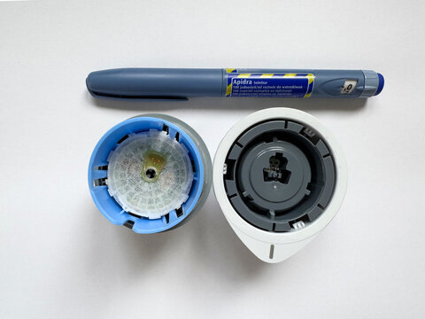 Poznan, Poland - 04.17.2025: Apidra insulin pen and FreeStyle Libre glucose monitoring system on white background