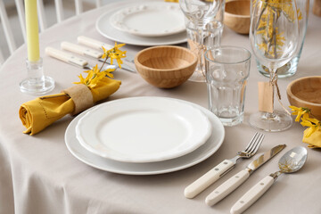 Elegant table setting with clean plates, cutlery and blooming tree branches, closeup