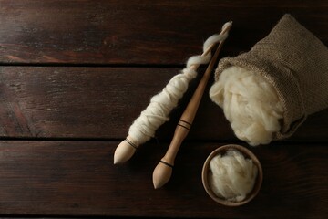 Soft wool and spindles on white wooden table, flat lay. Space for text