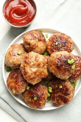 Delicious patties with green onions and ketchup on white table, top view