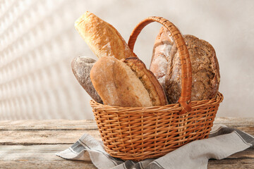 Different loaves of fresh bread in basket on wooden table, closeup