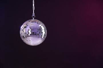 Shiny disco ball on dark purple background, space for text
