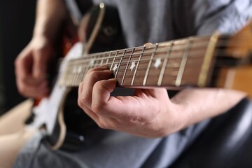 Obraz premium Man playing guitar on black background, focus on hand