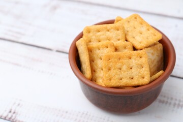 Tasty salty crackers on white wooden table, closeup. Space for text