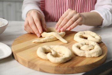 Woman shaping pretzels at table in kitchen, closeup