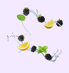 Fresh blackberries, lemon and splash of water on light background