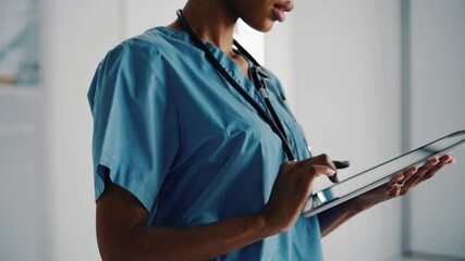 Healthcare provider using touchscreen tablet device to access digital medical records analytics and patient information during a consultation or examination in a modern clinic or hospital environment 
