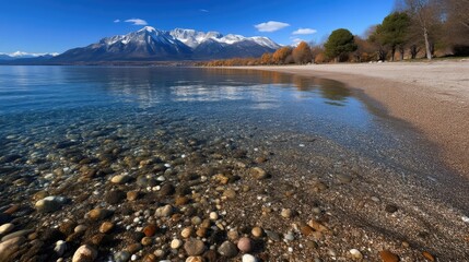 Pristine lake shore with mountain backdrop. Crystal-clear water reflecting a scenic autumnal landscape