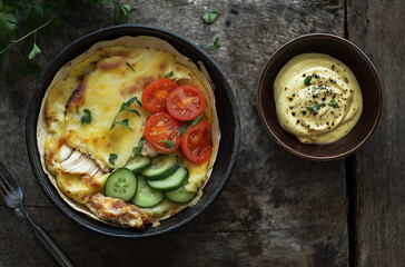 A bowl of colorful Middle Eastern cuisine with fresh vegetables and hummus, placed on a rustic wooden table, emitting an enticing aroma.