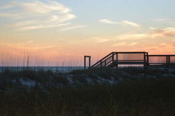 Boardwalk at sunset over sand dunes on Gulf of Mexico beach in Destin, Florida