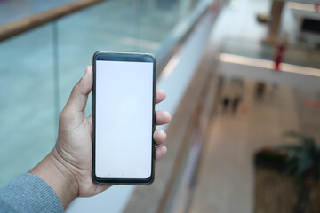 Person holding a smartphone in a modern indoor space