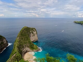 TRex rock island of Nusa Penida turquoise water cloudy sky © upen