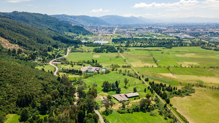 Fototapeta premium Aerial View of Lush Green Fields and Mountains Surrounding Northern Bogotá, Colombia