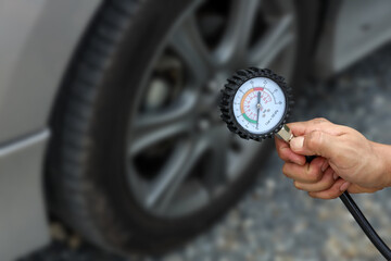 Auto mechanic holding car tire pressure check equipment tool to checking low tire pressure...