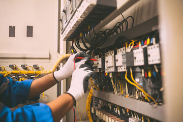 Electrical service technician use electricity measuring tools equipment checking electric current circuit breaker terminal panel and cable wiring main power distribution board for maintenance system.